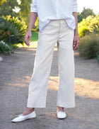 Person wearing beige pants and white shoes in a garden setting